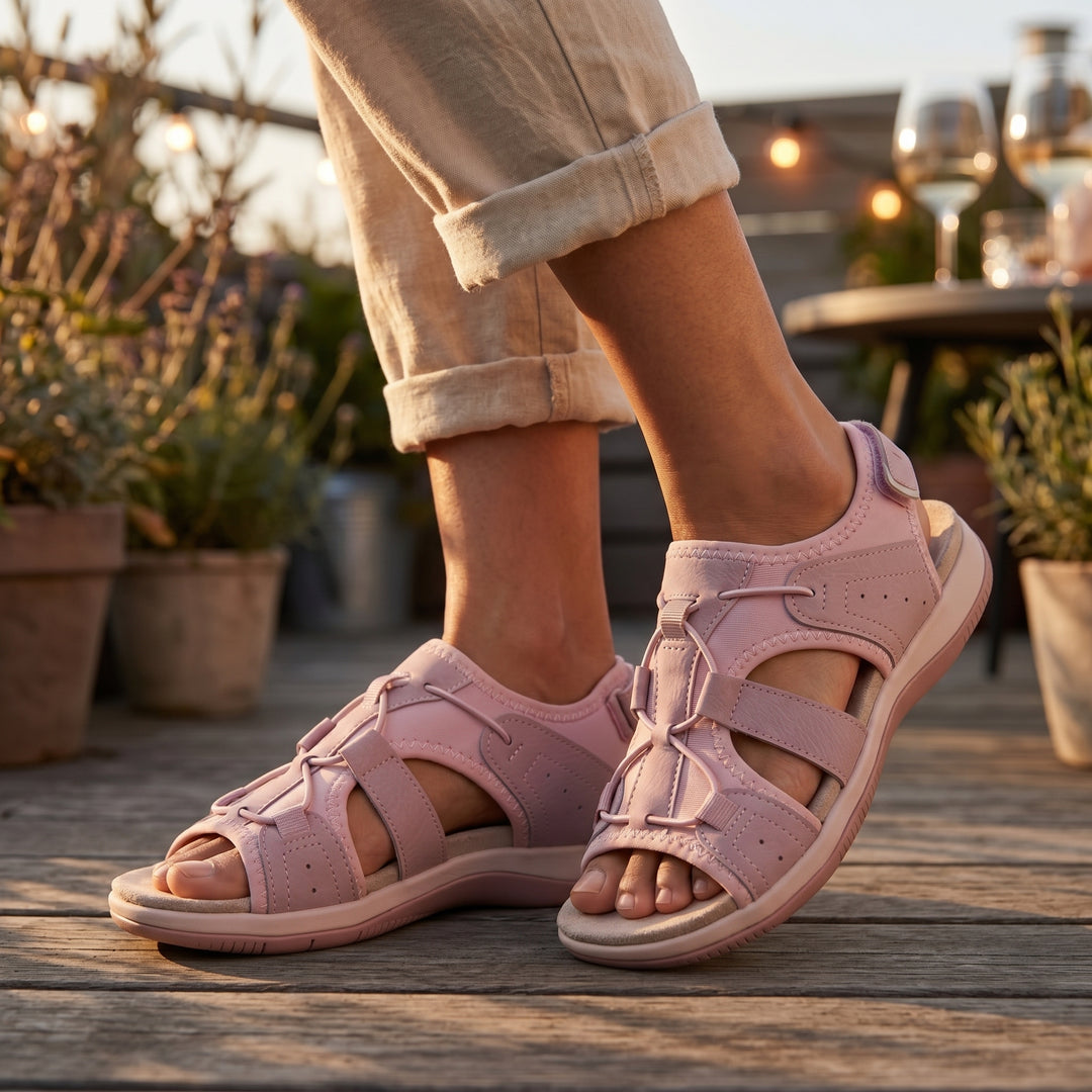 Orthopädische Sandalen in Rosa, am Fuß getragen auf Holzterrasse im Abendlicht