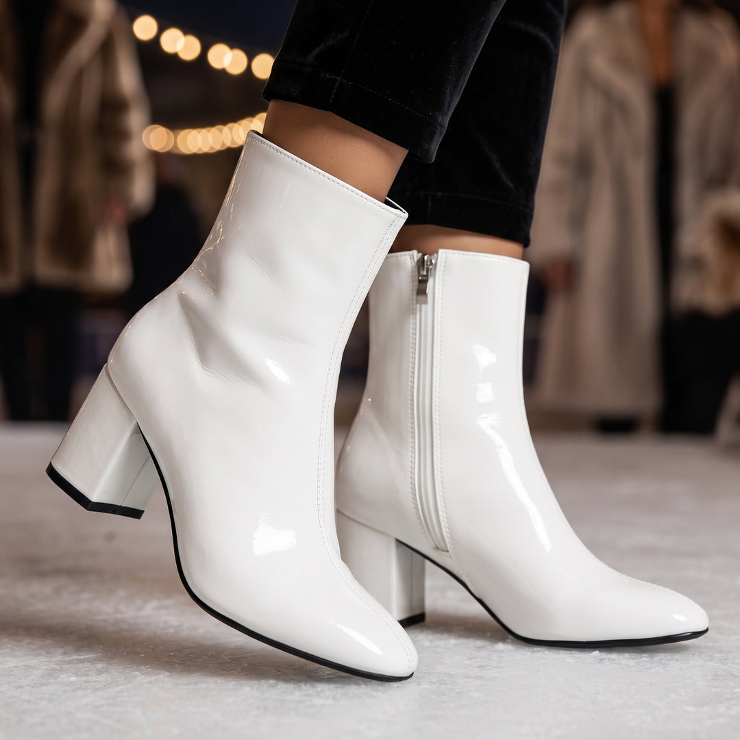 Weiße Stiefelette mit Lackoptik am Fuß, kombiniert mit schwarzer Hose