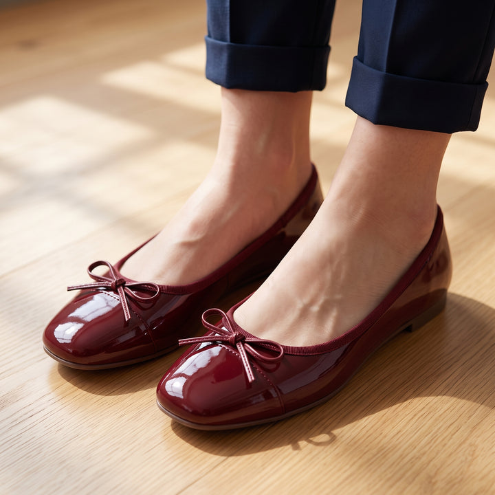 Bordeaux Lackleder-Ballerinas an Füßen, kombiniert mit dunkler Hose, Holzboden