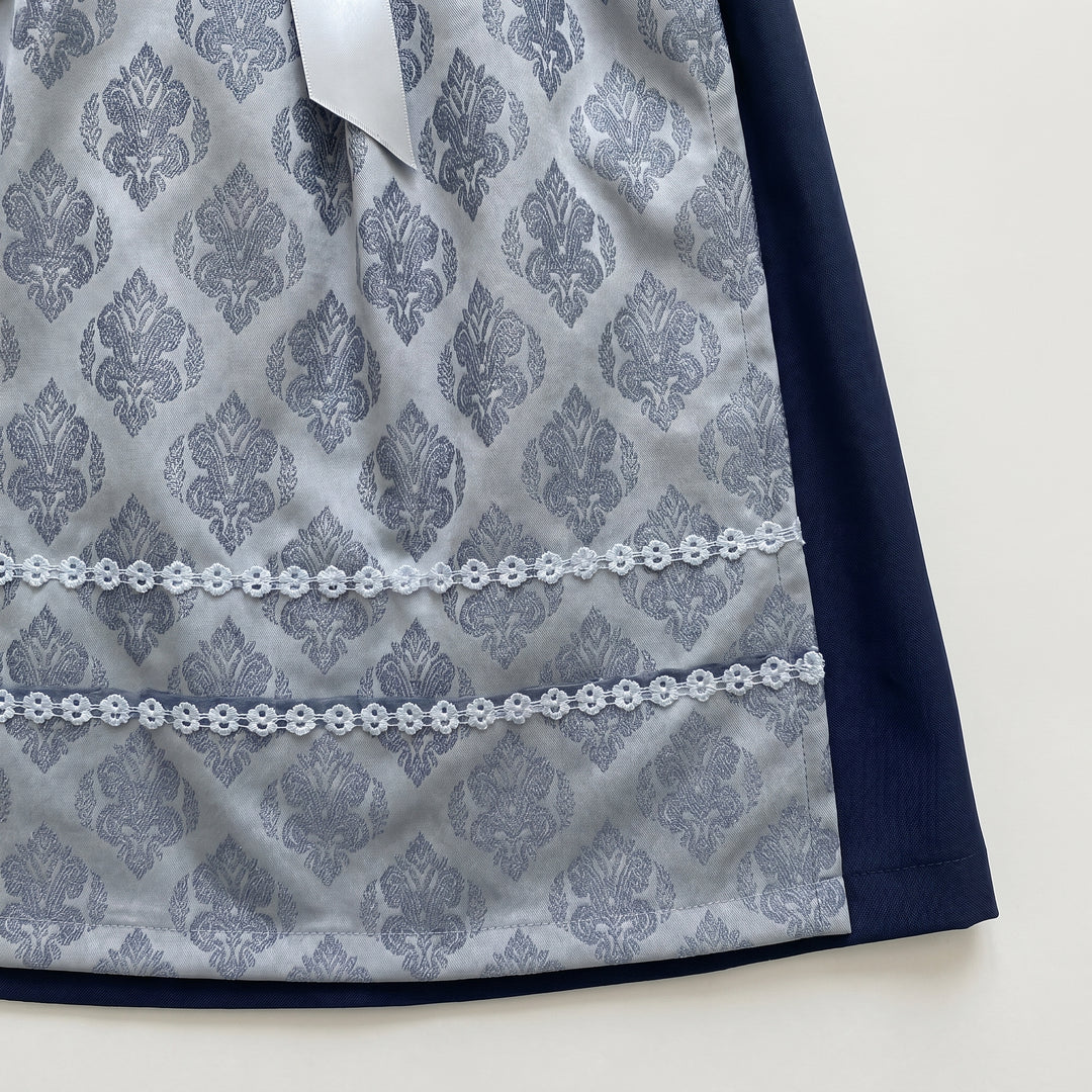 Dirndl Schürze Detailansicht, Jacquard-Ornamentmuster Hellgrau mit weißer Häkelspitzenborte