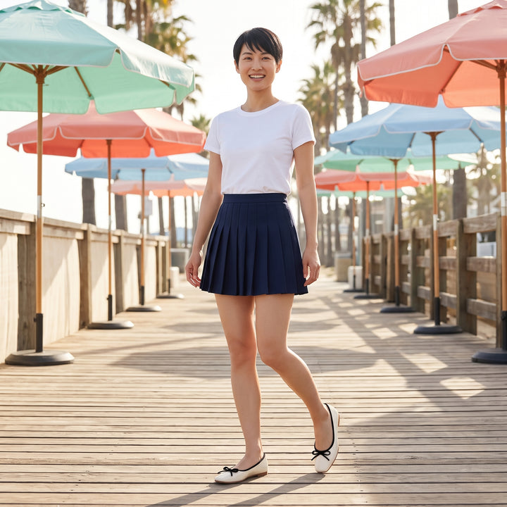 Model trägt Creme Ballerinas mit weißem T-Shirt und marineblauem Faltenrock