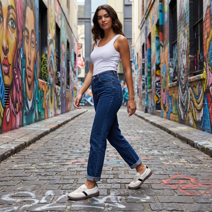 Weiß-Beige Sneaker am Model, Jeans und weißes Tanktop, urbaner Graffiti-Hintergrund