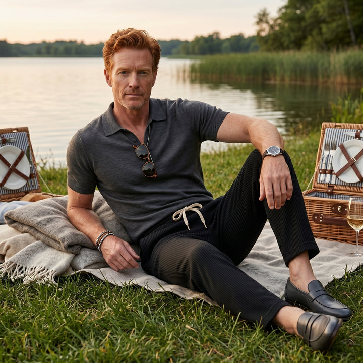 Herren Cordhose in Schwarz mit dunklem Poloshirt kombiniert, Picknick-Styling am See