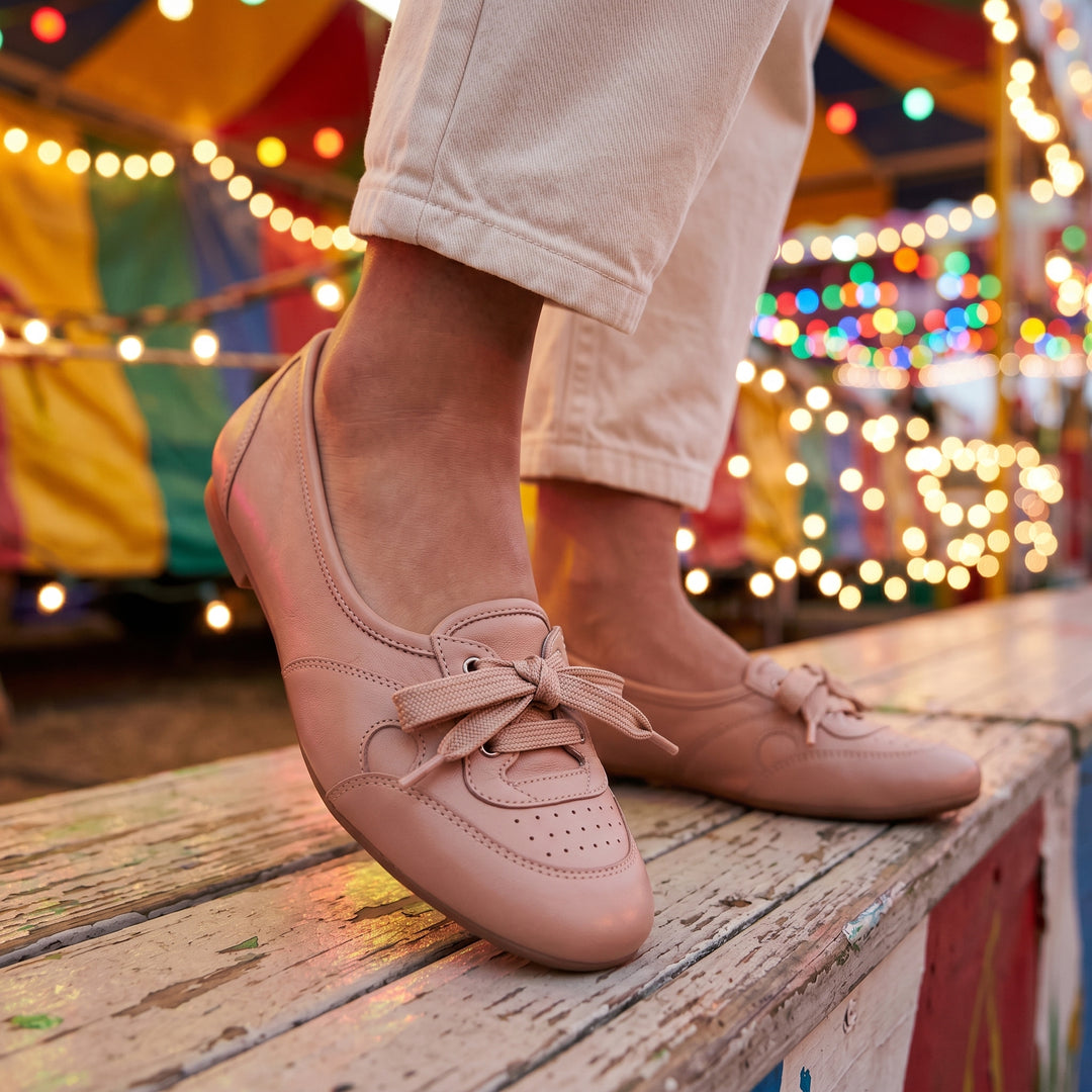 Apricot Damen-Ballerina am Fuß auf Holzbühne, Jahrmarkt-Ambiente, mit beiger Hose