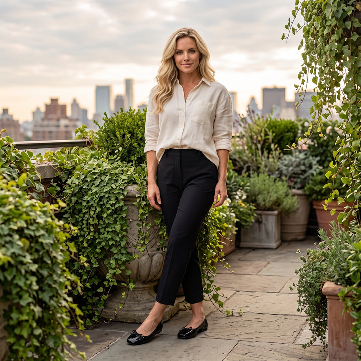 Model trägt schwarze Ballerinas mit cremefarbener Bluse und schwarzer Hose, Dachterrasse