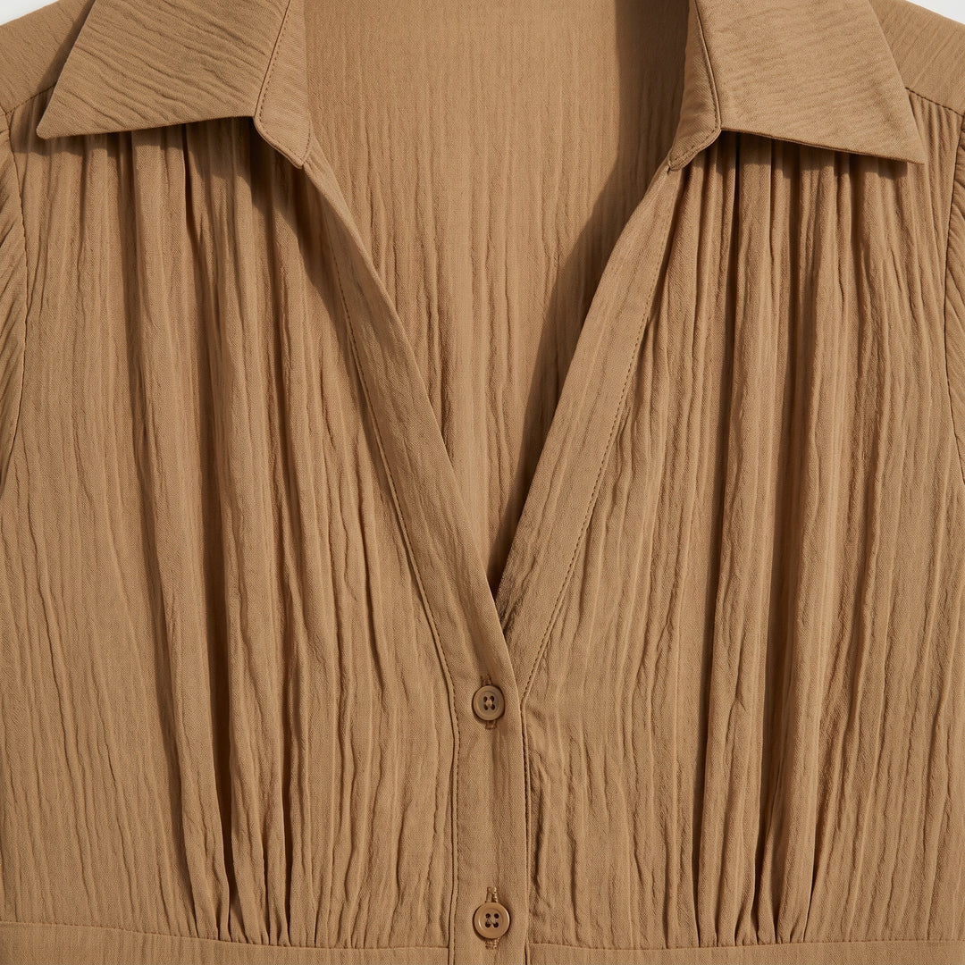 Detailansicht des V-Ausschnitts und Reverskragens am Plissee Maxikleid in Camel