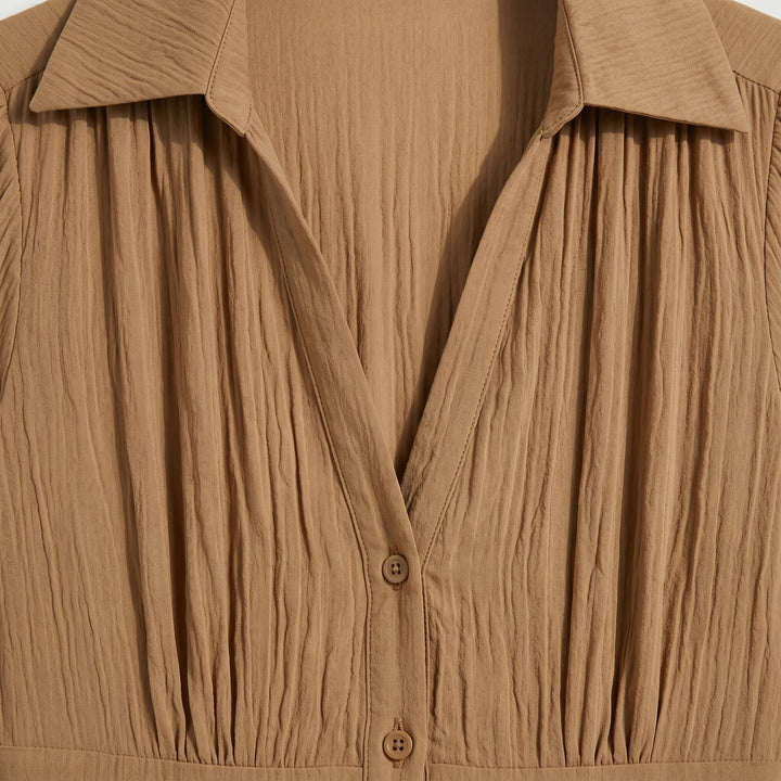 Detailansicht des V-Ausschnitts und Reverskragens am Plissee Maxikleid in Camel