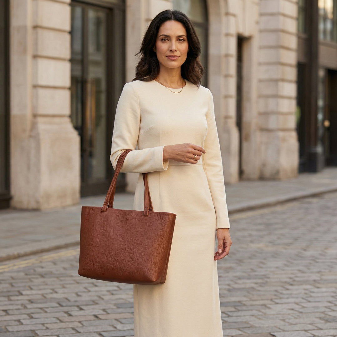 Damen trägt hellbraune Shopper über der Schulter, kombiniert mit Cremweißem Maxikleid