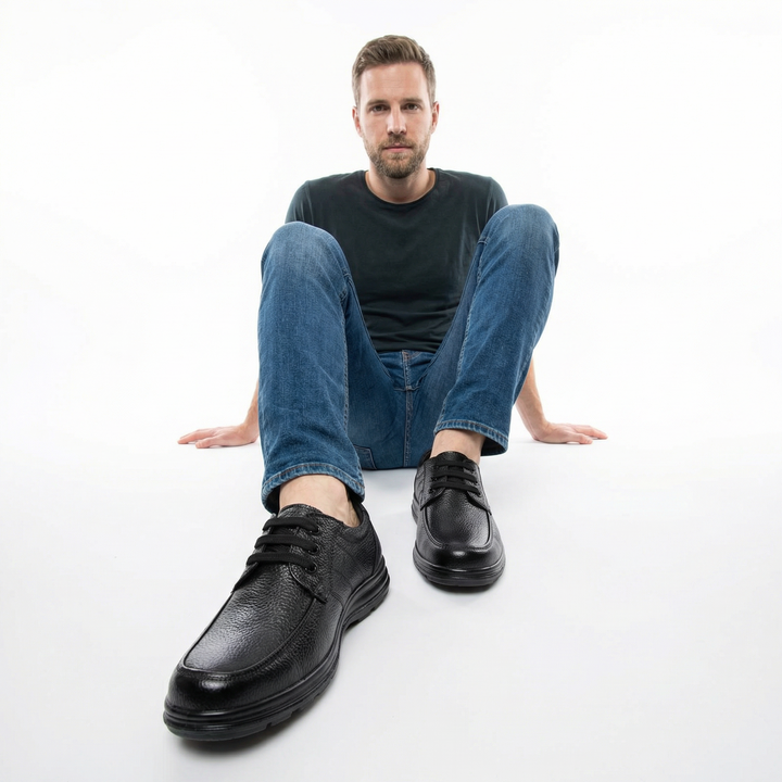Herren trägt schwarze Lederschnürschuhe sitzend, kombiniert mit Jeans