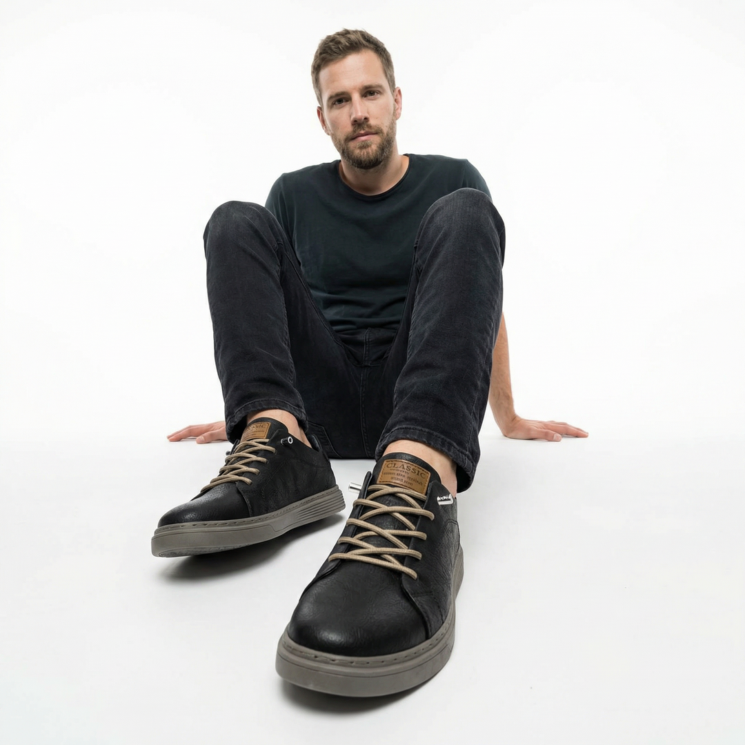 Herren trägt schwarze Leder-Sneaker mit Jeans, Seitenansicht