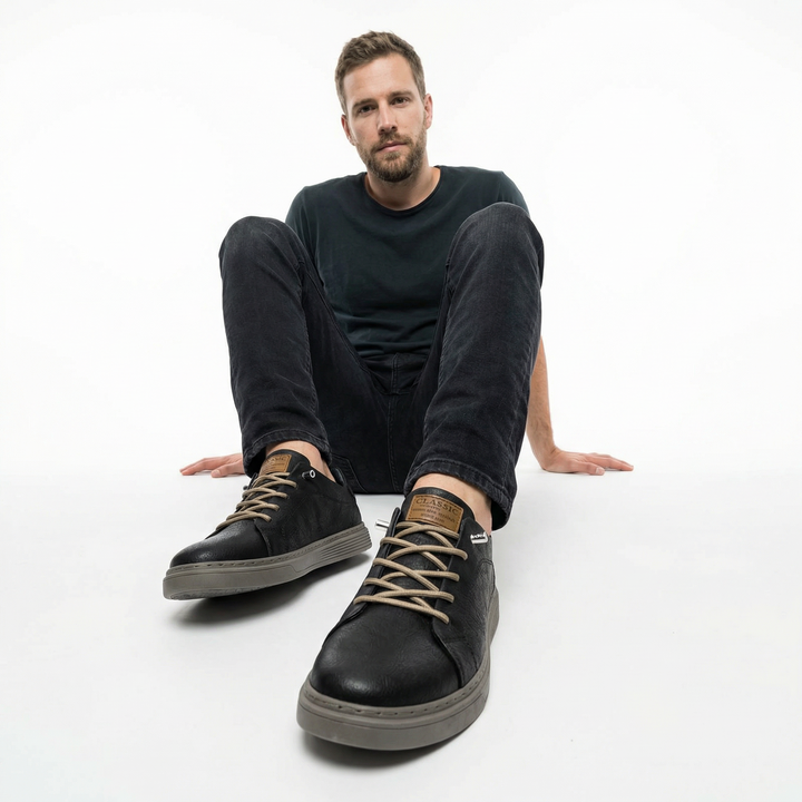 Herren trägt schwarze Leder-Sneaker mit Jeans, Seitenansicht