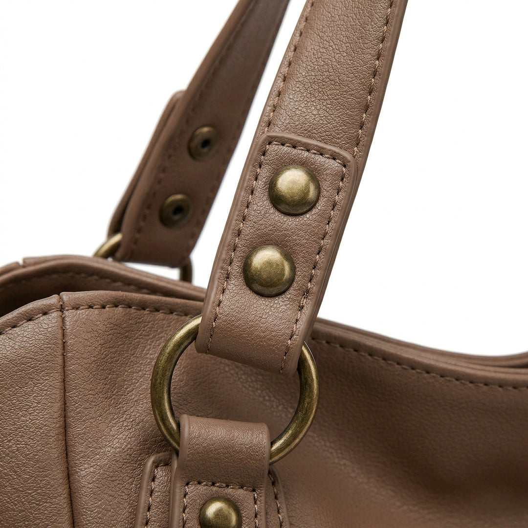 Detailaufnahme Henkelansatz taupefarbene Tasche mit goldenen Nieten und D-Ring
