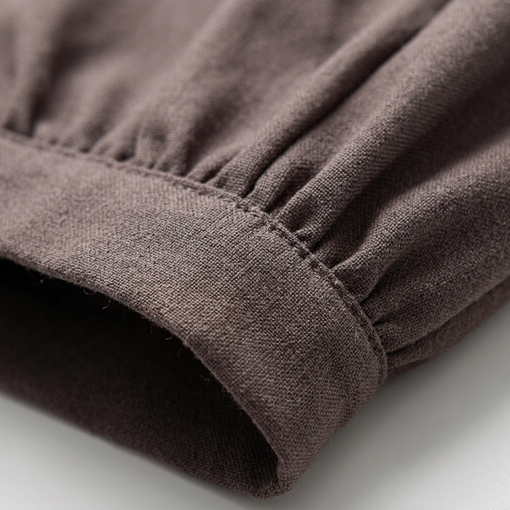 Detailaufnahme Stoffstruktur und Saum der dunkelbraunen Hose