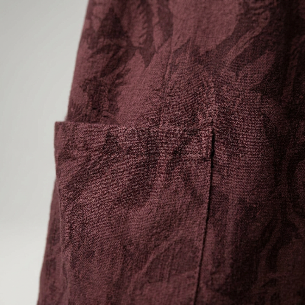 Detailaufnahme der aufgesetzten Tasche am weinroten Midikleid